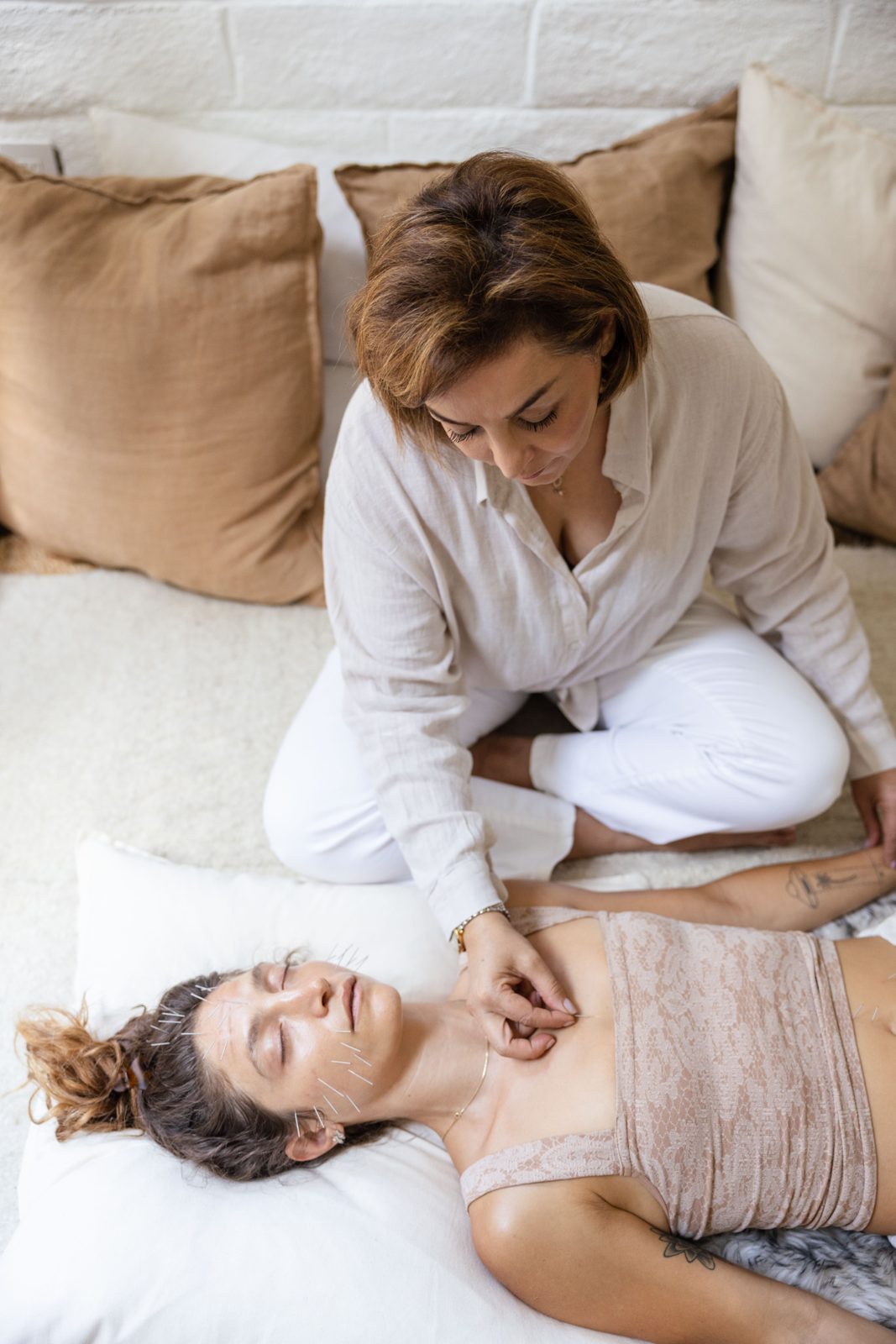 Vida Pirata sitting on the floor beside a patient, placing a needle below the collarbone.